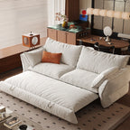 Cream sofa bed with its pull-out sleeping section extended beneath loose back cushions and padded arms.
