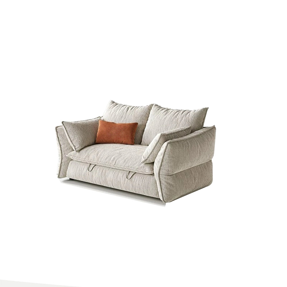 Compact cream sofa bed with two loose back cushions, padded arms and an orange accent pillow.