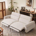 Cream two-seat reclining sofa with both footrests extended and padded arms in a bright room.