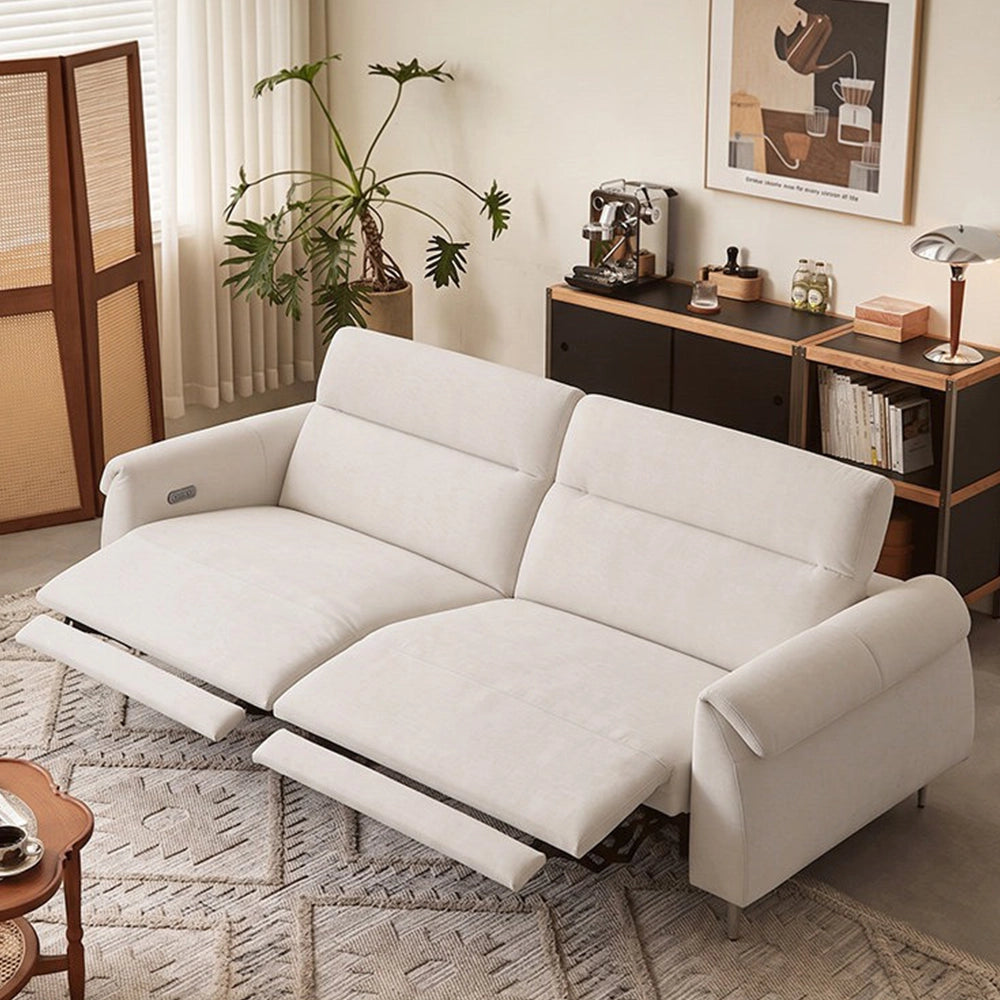 Cream two-seat reclining sofa with both footrests extended and padded arms in a bright room.