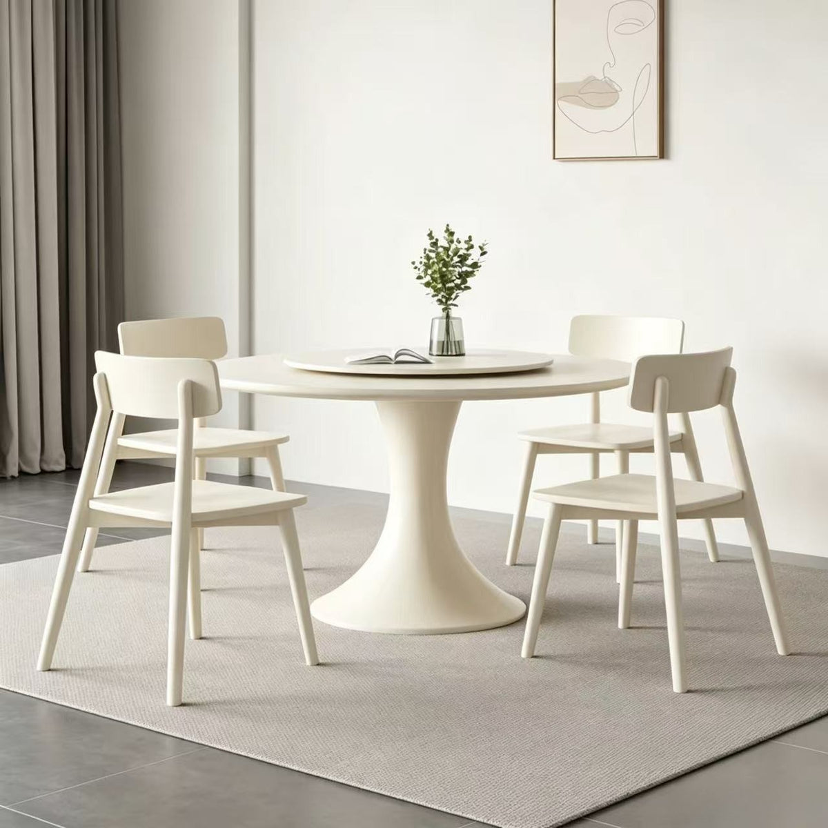 Cream circular dining table with a flared pedestal and raised turntable in a neutral dining room.