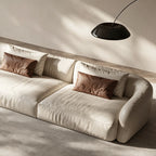 Close-up of the cream sofa's broad seat cushions, rounded arm and contrasting accent pillows.