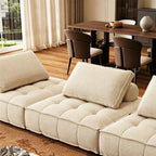 Close-up of the cream sofa's separate tufted seat sections and rectangular back cushions.