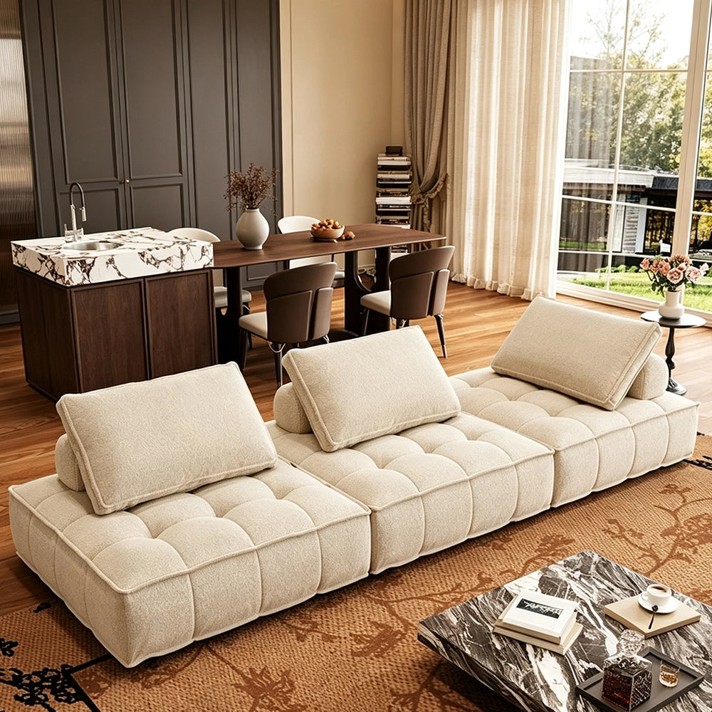 Wide angled view of the cream three-section modular sofa on a patterned rug.