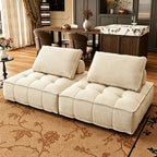 Two cream armless modular sofa sections with tufted seats and separate back cushions.