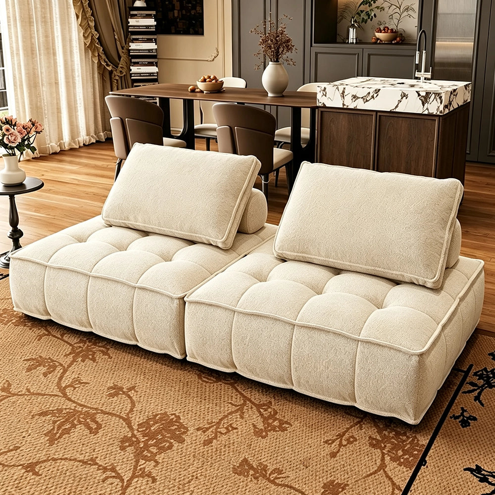 Two cream armless modular sofa sections with tufted seats and separate back cushions.