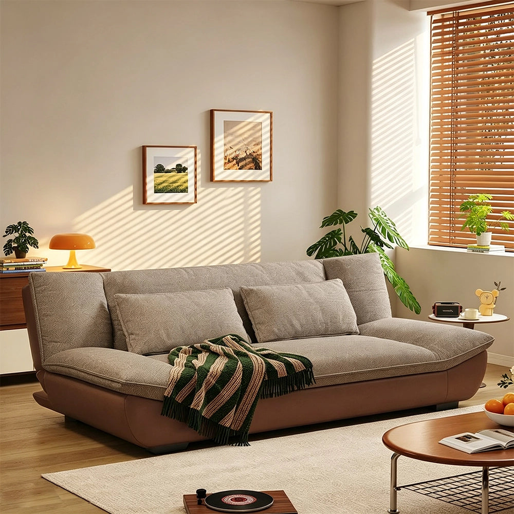 Angled room view of the taupe cushioned sofa with an upswept brown base and low dark feet.