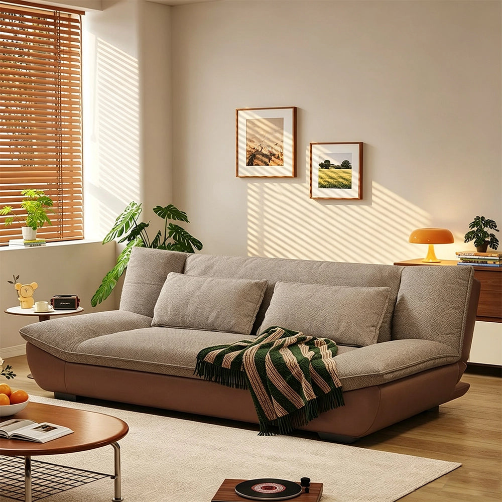 Sofa with taupe textured cushions, rounded arms and a smooth curved brown base in a living room.