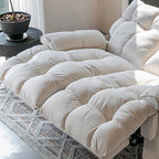 Detail of the cream loveseat's deeply cushioned seats and extended footrests.