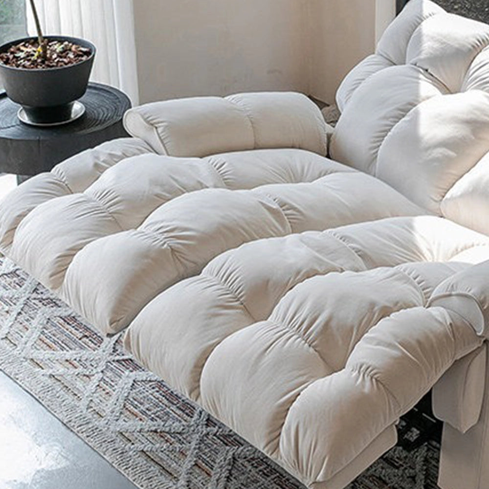 Detail of the cream loveseat's deeply cushioned seats and extended footrests.