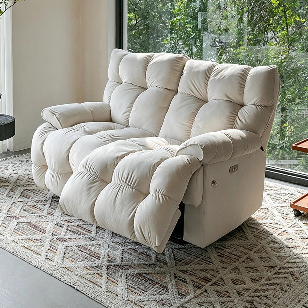 Cream two-seat reclining loveseat in upright form beside garden-facing windows.