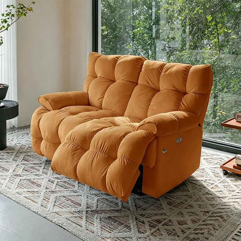 Orange deeply cushioned reclining loveseat in upright form beside garden-facing windows.