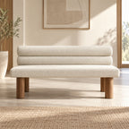 Front view of the cream upholstered bench with a double-roll backrest and cylindrical wood-tone legs.