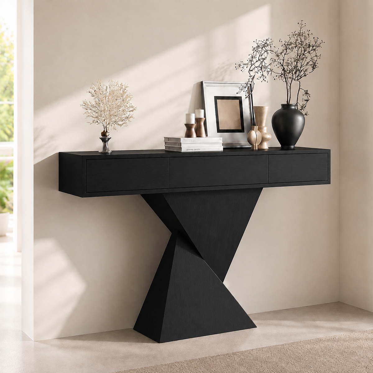 Black version of the three-drawer console table with a geometric base, styled against a pale wall.