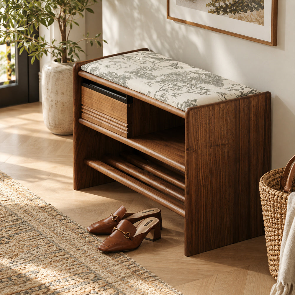 Entryway bench with a cream landscape-patterned seat cushion, brown frame, grooved drawer, open cubby and lower shoe rack, viewed from above.