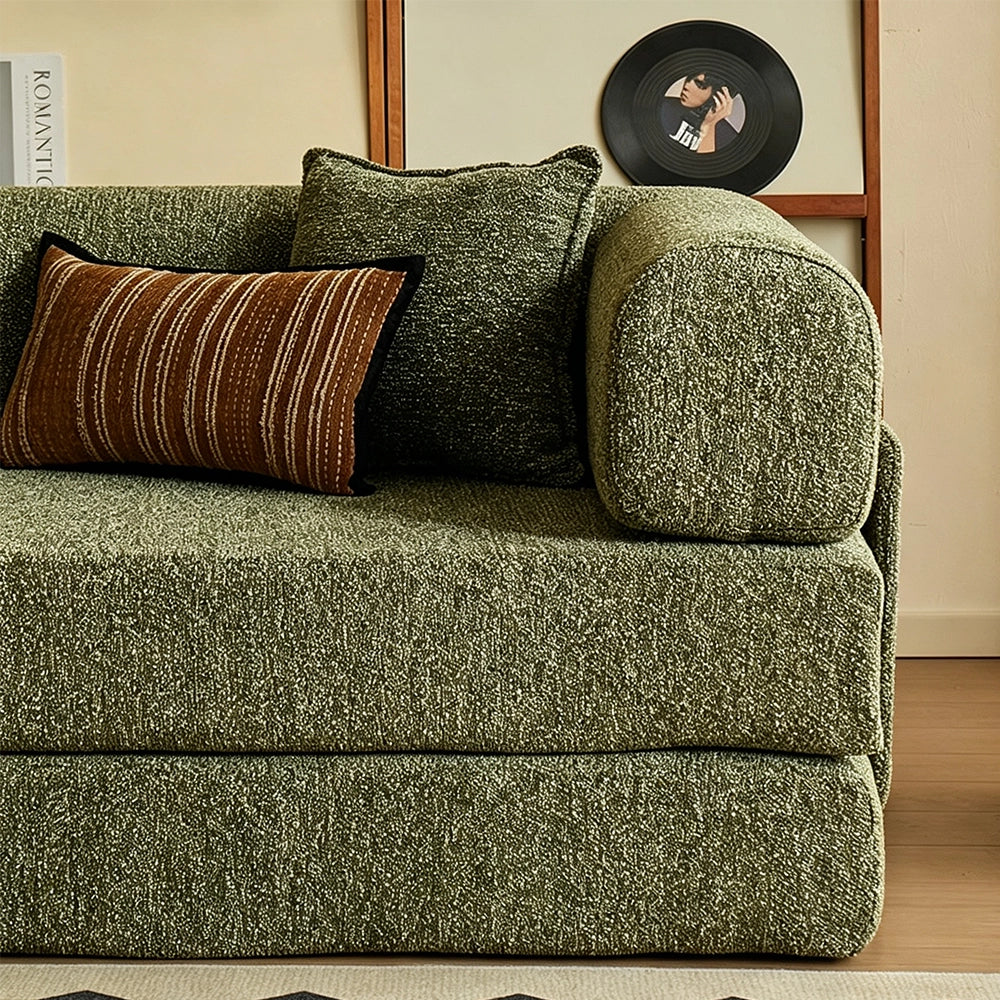 Close-up of the green sofa bed's rounded arm and stacked cushion base.
