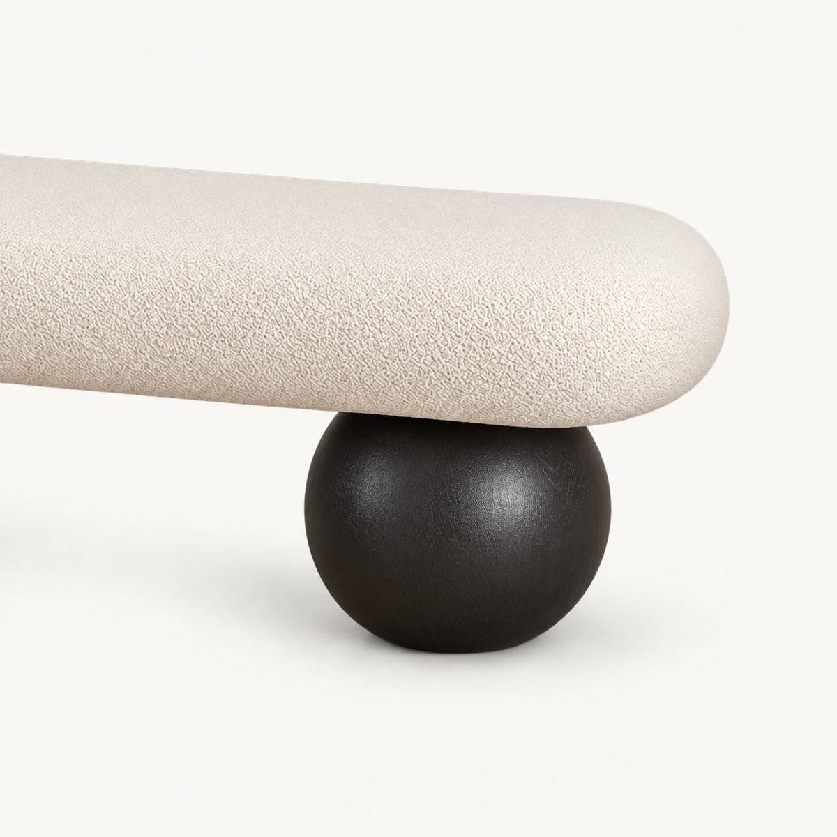 Close-up of the cream bench's rounded upholstered end and black spherical support.