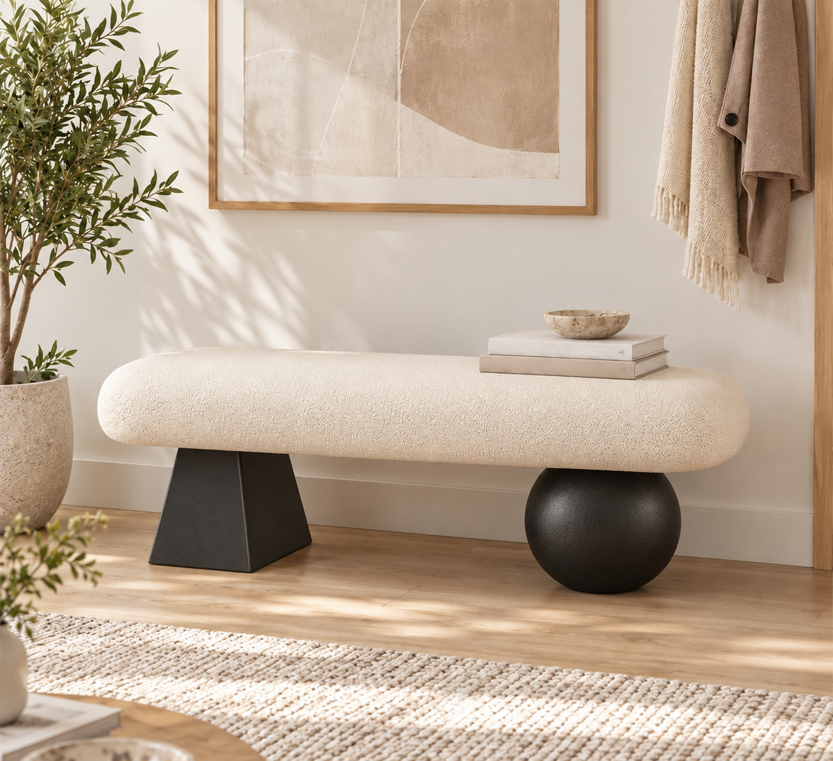 Cream upholstered bench on one black tapered support and one black ball-shaped support in an entryway.