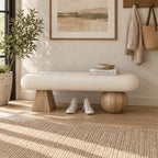Front view of the cream bench with mismatched light wood-tone geometric supports and shoes beneath the seat.