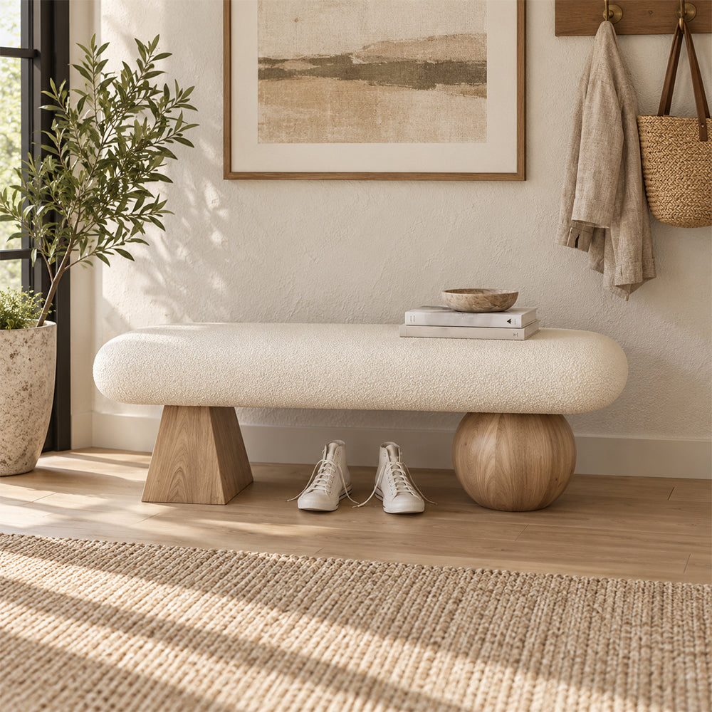 Front view of the cream bench with mismatched light wood-tone geometric supports and shoes beneath the seat.