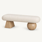 Cream rounded upholstered bench with a light wood-tone tapered block leg and a light wood-tone spherical leg.