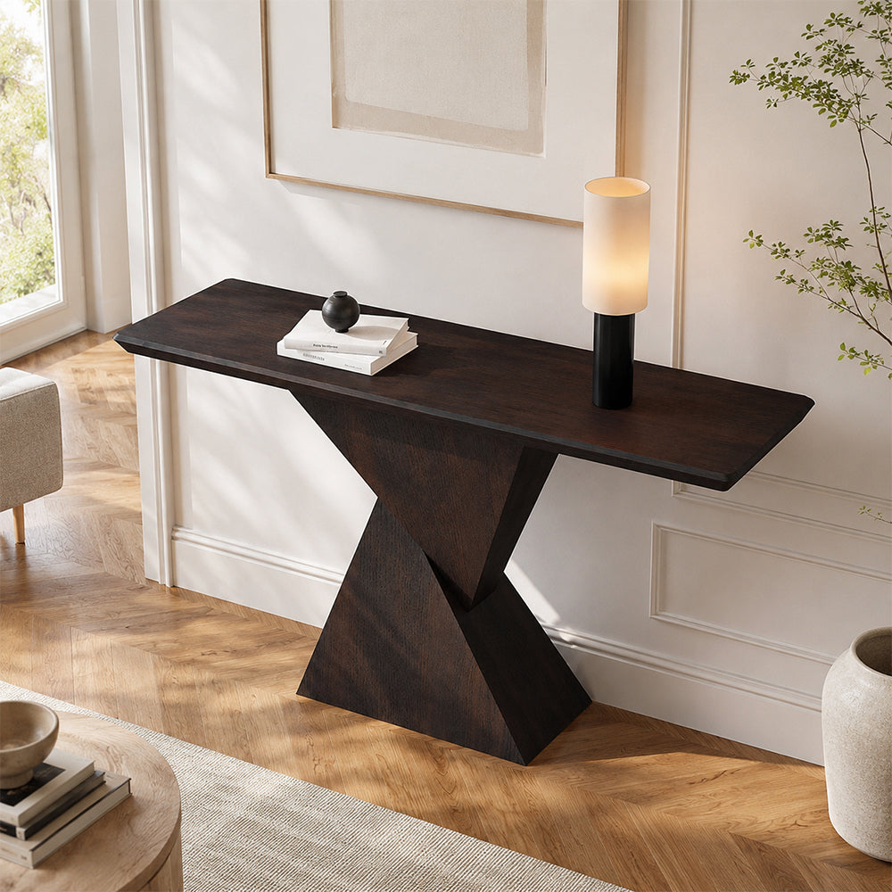 Angled view of the dark console table's narrow top and geometric pedestal in an entryway.