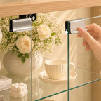 Hand opening a clear glass cabinet door using its rectangular metal handle.
