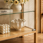 Close-up of the cabinet's glass shelf, lower frame and clear door beside ceramic ornaments.