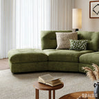 Front detail of the green sofa's extended end seat and tufted back cushions.