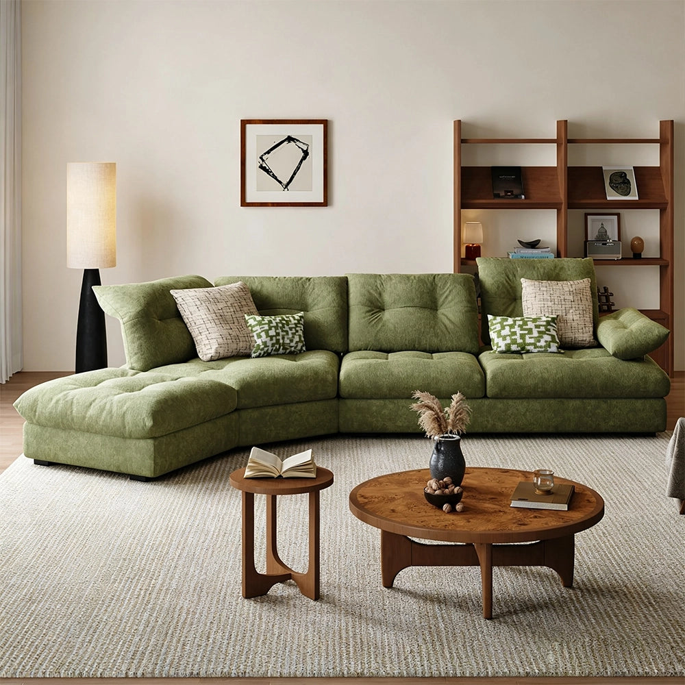 Green tufted sectional sofa with a curved arrangement and extended end seat in a bright living room.