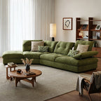 Green sectional sofa with a chaise-like end and raised angled arm cushion beside wooden coffee tables.