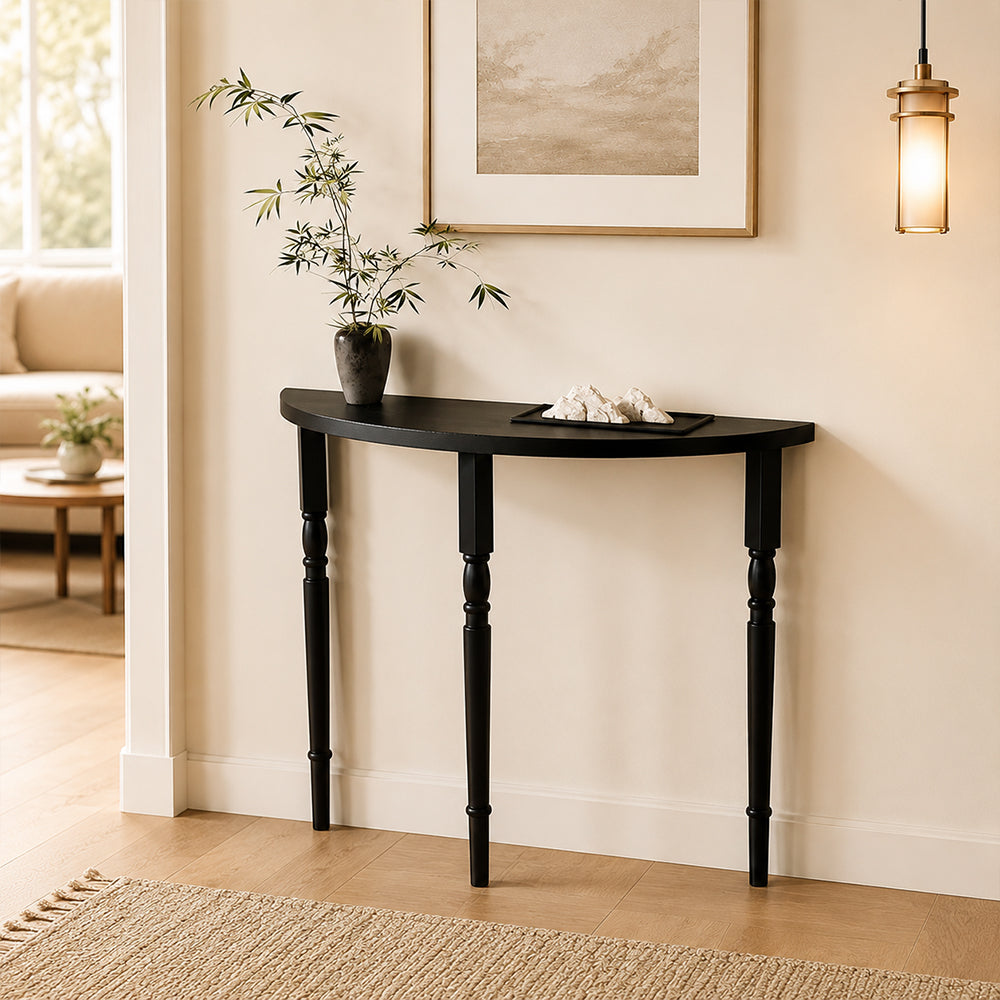 Black half-moon console table with slender turned legs, styled with greenery in an entryway.