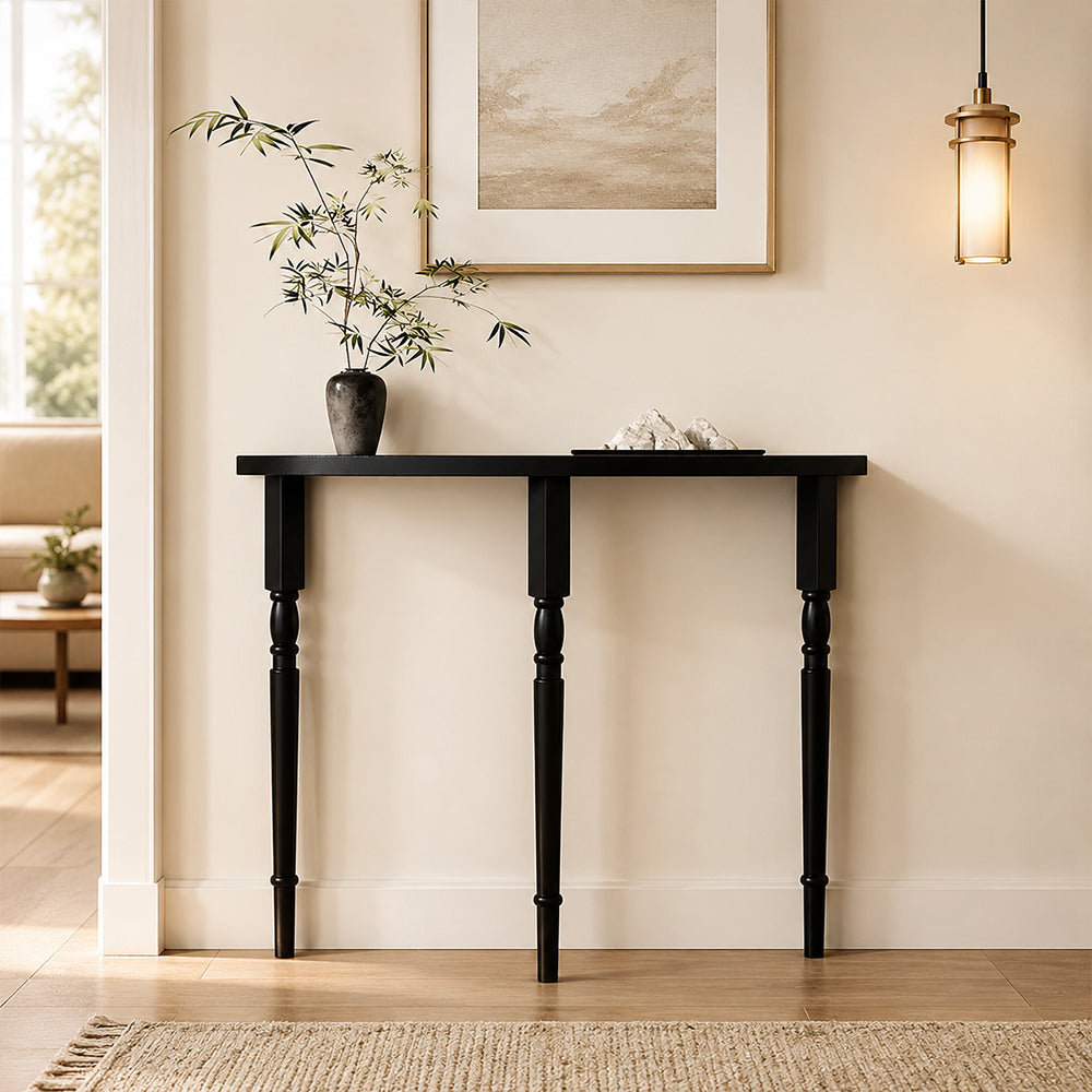 Front view of the black half-moon console table beneath framed artwork.