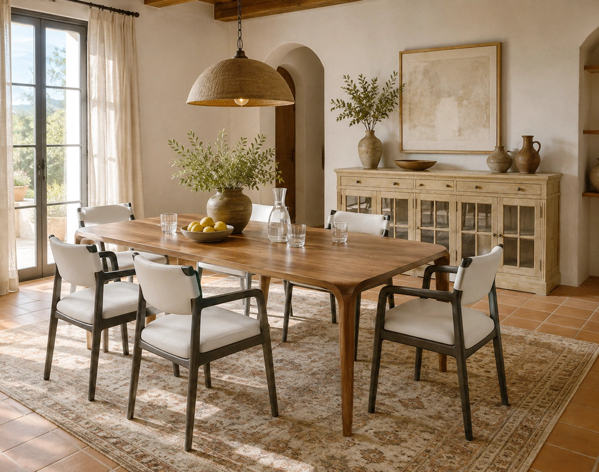 Brown dining table with upholstered chairs, woven pendant lights and a glass-front sideboard in a bright room.