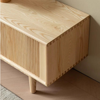Close-up of the media console's wood-grain top, fluted front and visible corner joints.