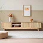Light wood-tone media console with fluted doors and an open shelf section, styled beneath artwork.