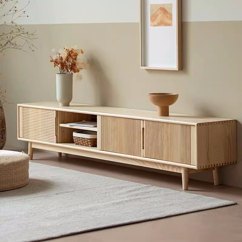 Angled view of the light media console showing fluted fronts, open media shelves and short legs.