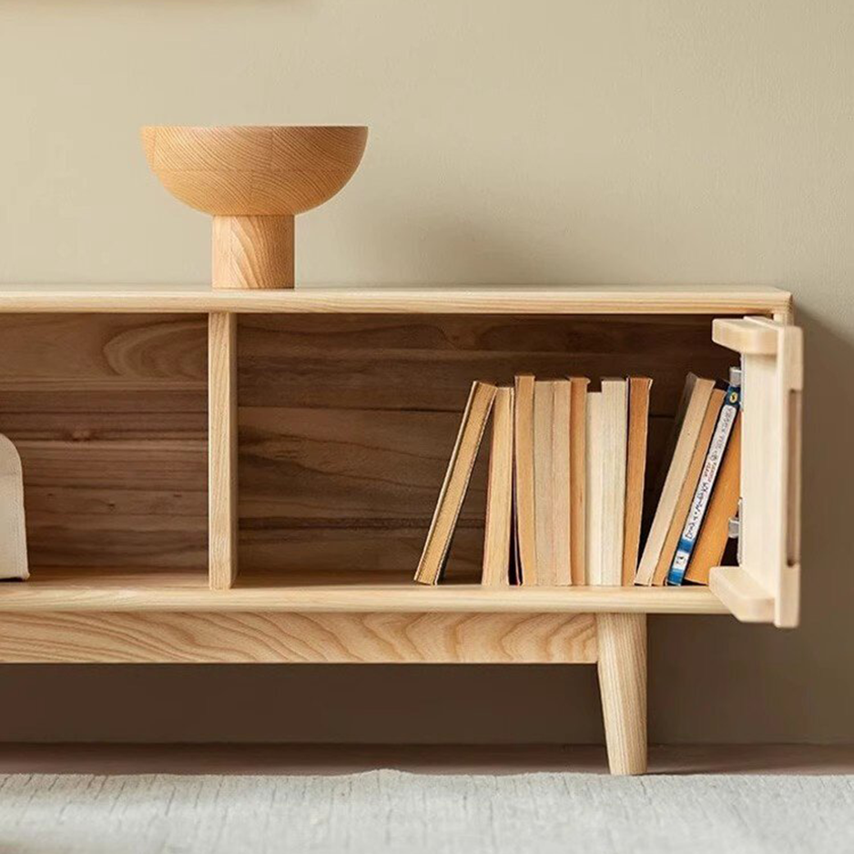 Detail of an open storage compartment in the light media console, with books beside a hinged door.