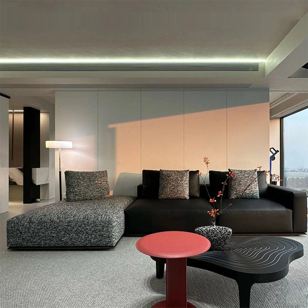 Front view of the low dark sofa with contrasting gray textured chaise and accent cushions.