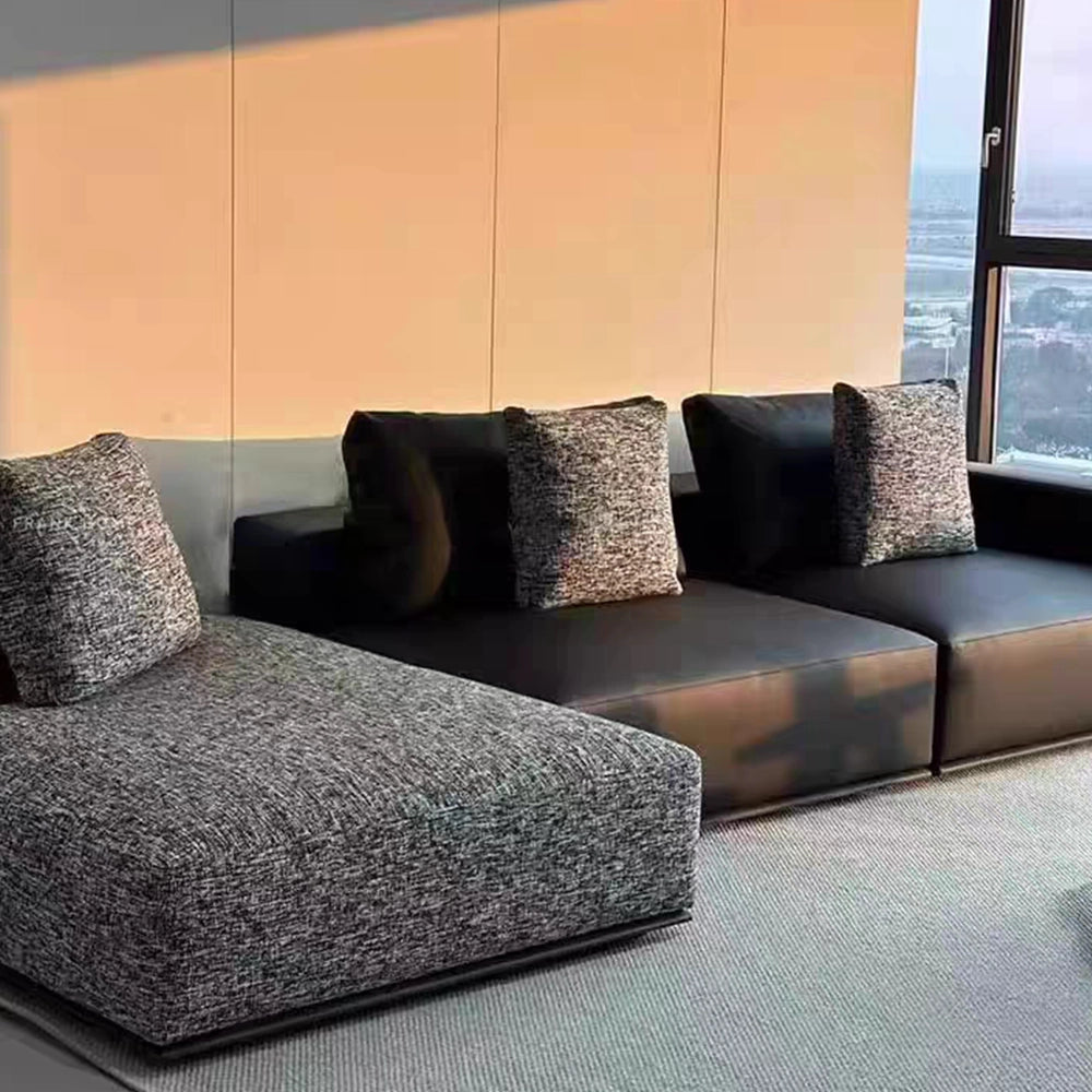 Angled detail of the modular sofa's gray textured chaise and dark smooth seats.