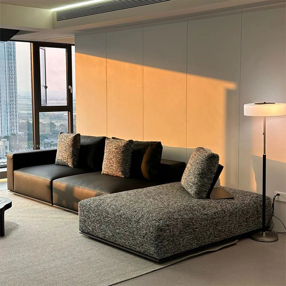 Dark modular sofa with a gray textured chaise on the right as pictured in a sunlit room.