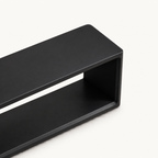 Overhead detail of the black bench's long top and rounded end edges.