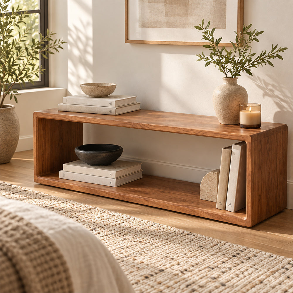 Angled view of the brown open-frame bench with books and a vase on top.