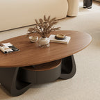 Overhead angled view of the oval brown coffee table top and dark sculptural storage base.