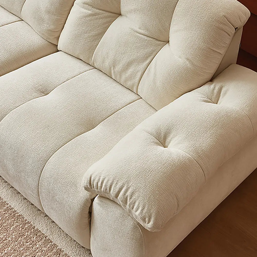 Overhead close-up of the cream sofa's padded arm, seat and segmented back cushion.