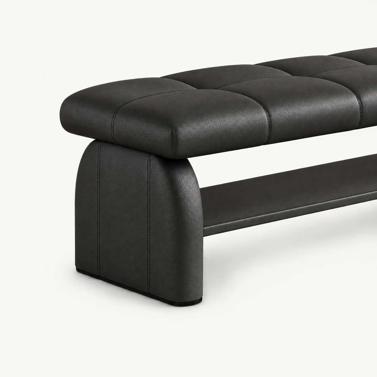 Angled detail of the black bench's rounded upholstered side support, stitched cushion and lower shelf.