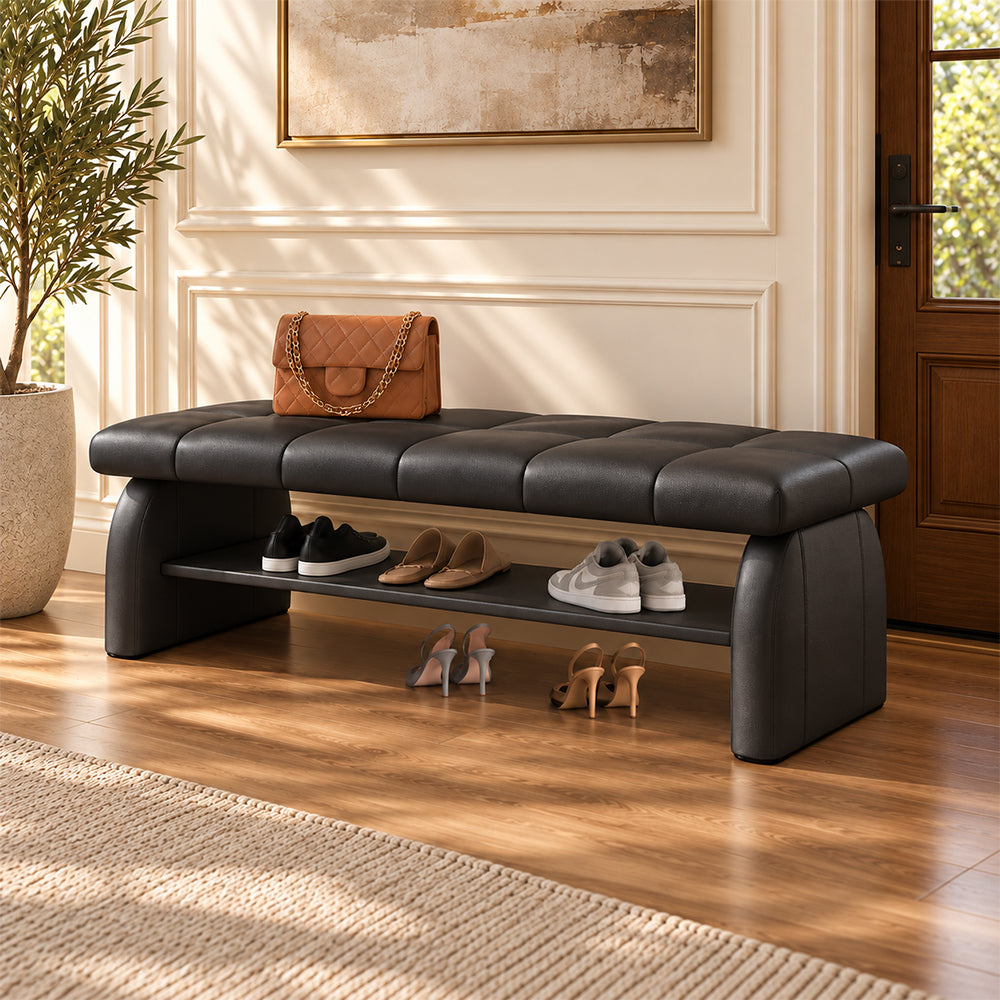 black padded shoe bench with a stitched seat, broad upholstered supports and a lower shelf holding shoes.