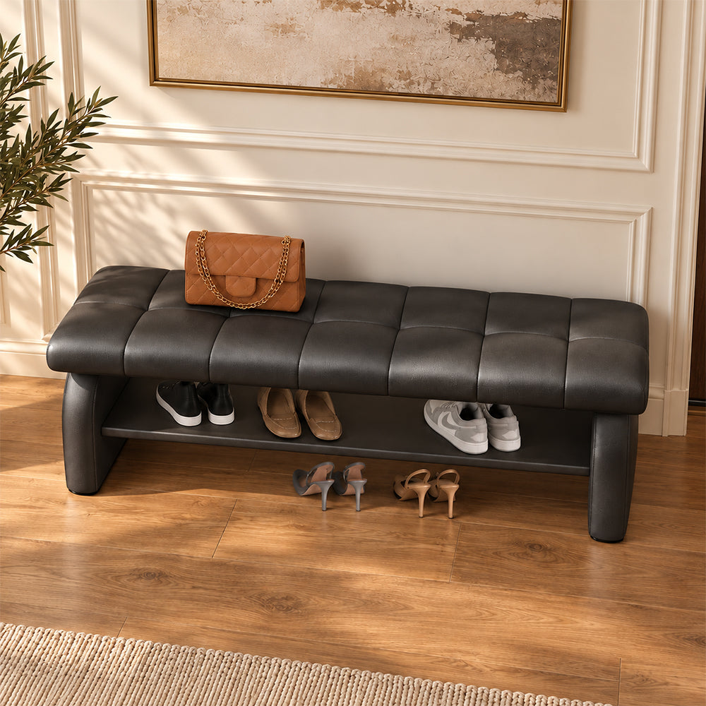 Overhead angled view of the black bench's stitched cushion, broad side supports and shoe shelf.