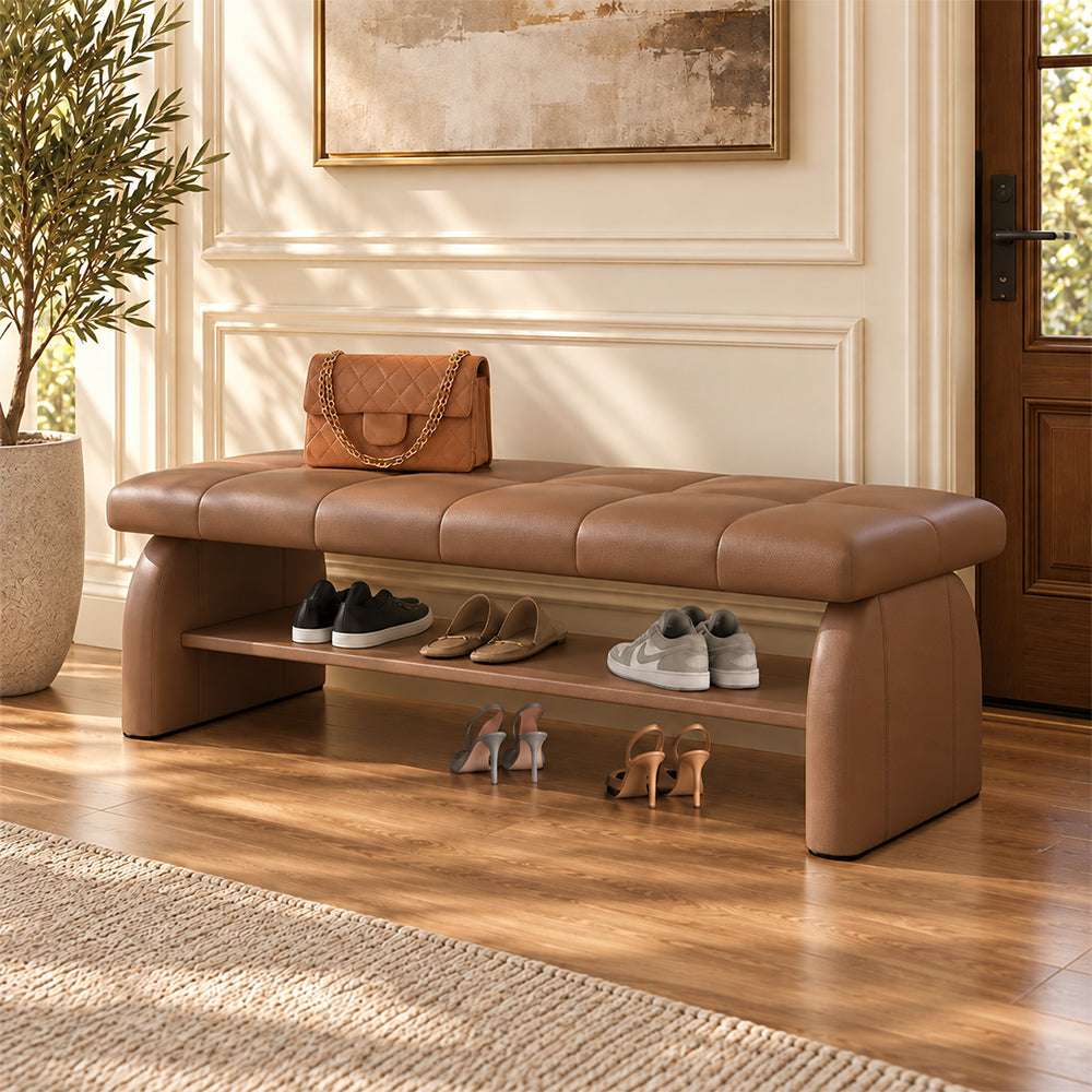 brown padded shoe bench with a stitched seat, broad upholstered supports and a lower shelf holding shoes.