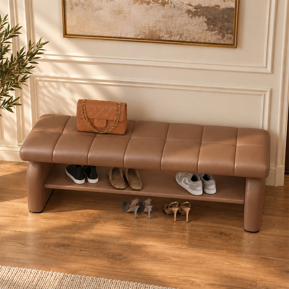 Overhead angled view of the brown bench's stitched cushion, broad side supports and shoe shelf.